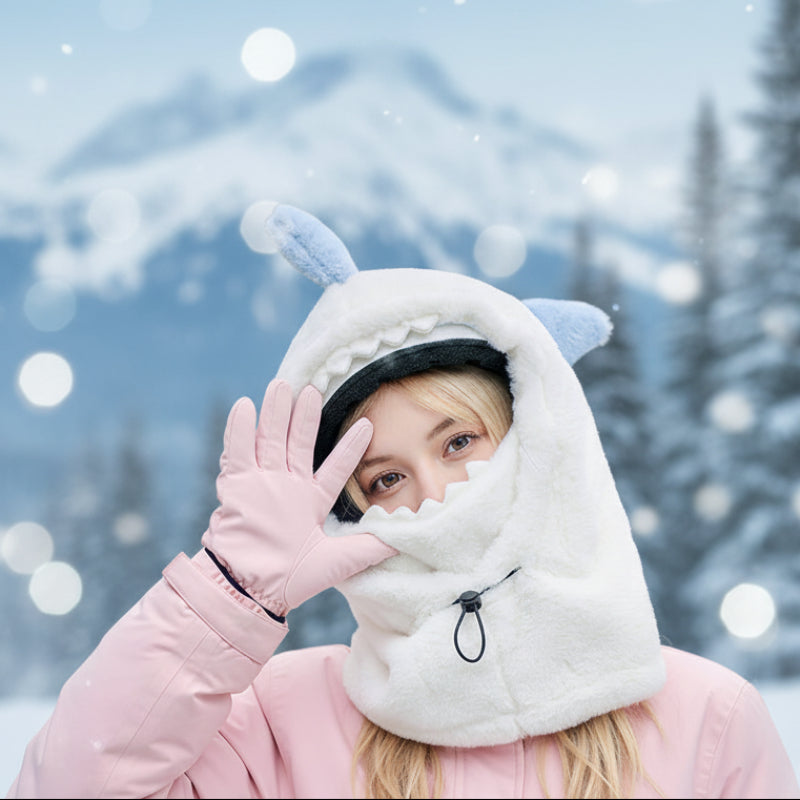 Person wearing a white plush hood with blue ears, covering their head and neck, outdoors.